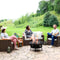 Three friends sitting on patio furniture talking around a mesh strip cutout fire pit with a burning fire on a stone patio