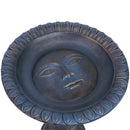 Detail of sun with a face design in the bottom of the blue, concrete bird bath bowl.
