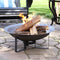 Small, cast iron fire pit burns while a man sits in a black Adirondack chair.