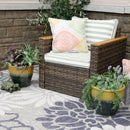 Wicker patio chair with green stripe cushions with one two-toned yellow-blue planter with plants placed on each side.