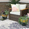 Wicker patio chair with green stripe cushions with one two-toned yellow-blue planter with plants placed on each side.
