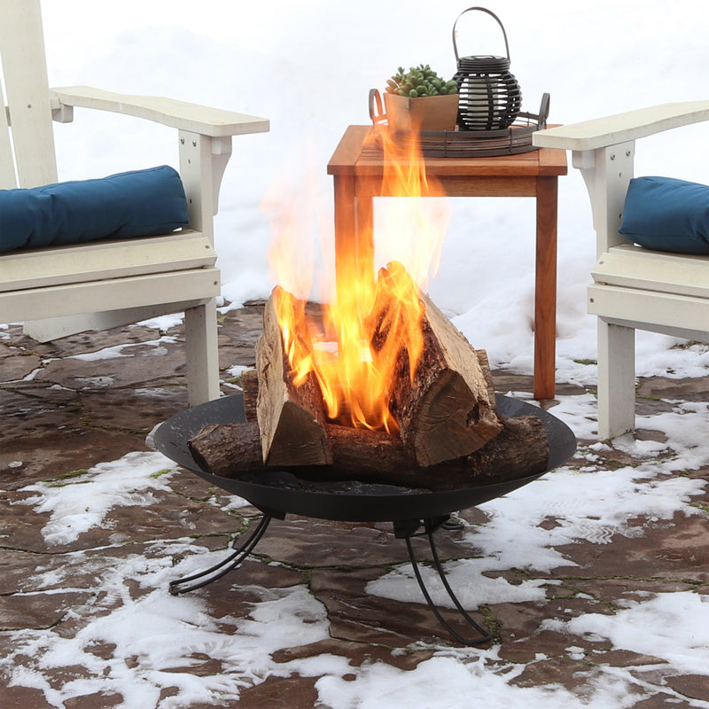 Portable easy-folding fire pit burning fire on a stone patio surrounded by two adirondack chairs 