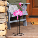 Metal pink flamingo on a wooden porch, behind it sits a gray Adirondack chair with a grey geometric pillow.