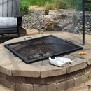 Black, square cooking grate over a burning stone fire pit.