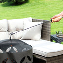 Fire poker with wood handle being used to lift a spark screen off of a hot fire pit.