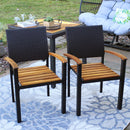 Two acacia wood with rattan seat backs chairs on outdoor patio with floral rug, in front of square patio table