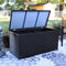 Black resin rattan deck box and acacia wood handles with lid open outdoors on a floral rug