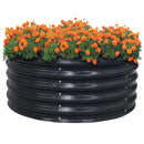 Black, round, raised metal garden bed with orange flowers.