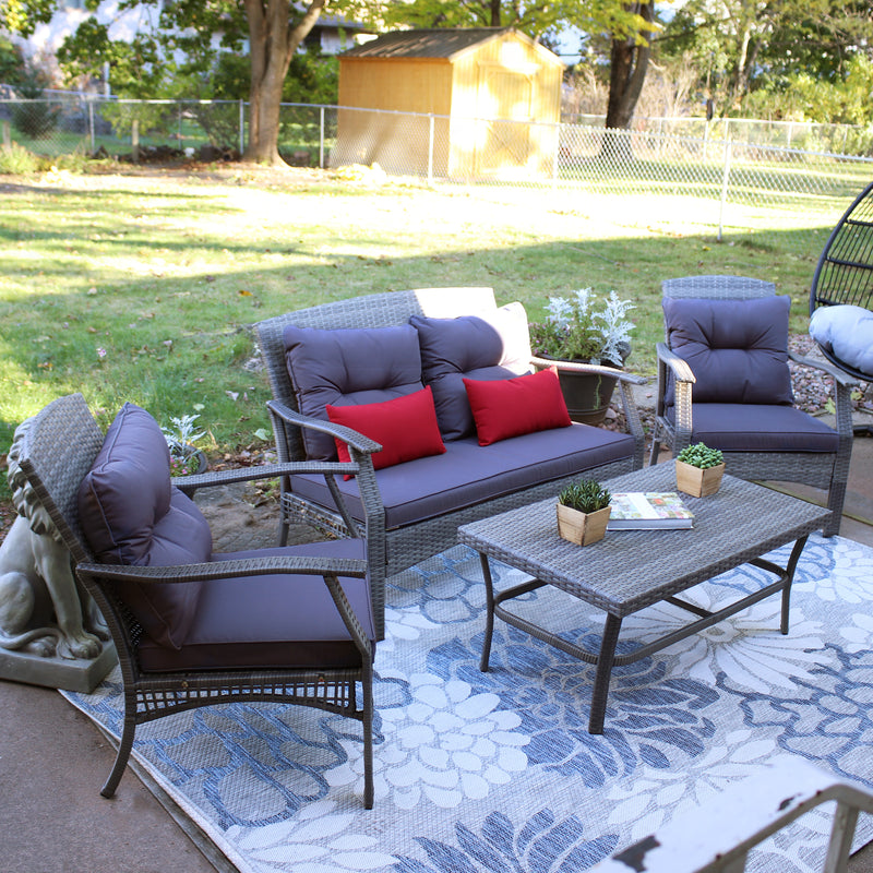 Kingsley 4-piece patio conversation set with gray patio cushions sitting on outdoor rug that is coving a outdoor patio