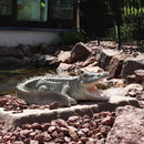 Outdoor polystone open-mouthed crocodile statue sitting on a stone next to a pond