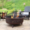 Bronze fire pit with star and moon cut outs having it's spark screen removed by a fire poker.